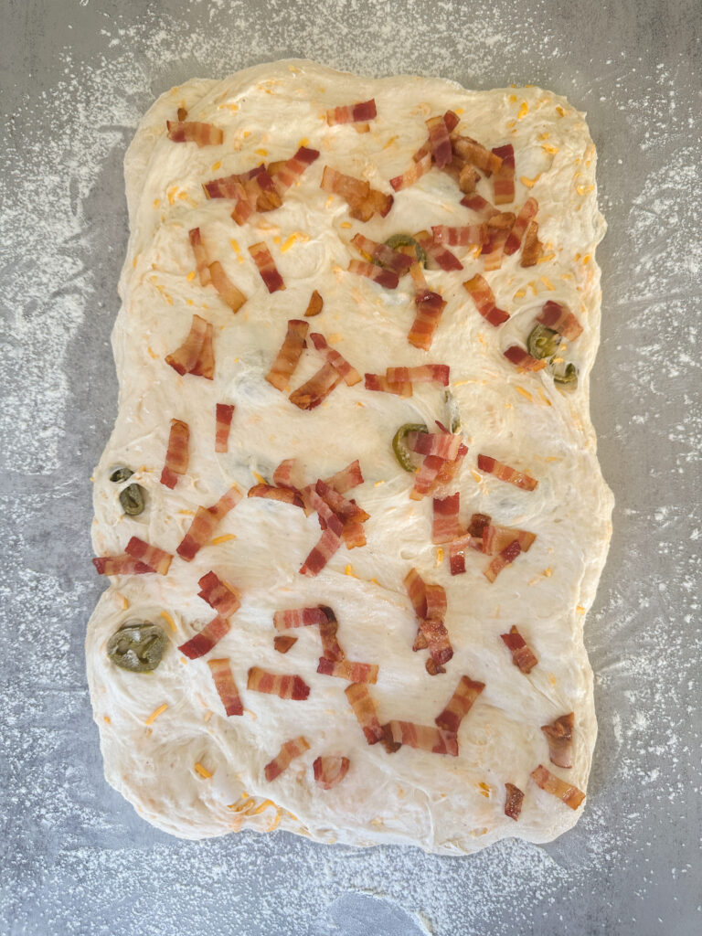 Sprinkle bacon on top of the dough