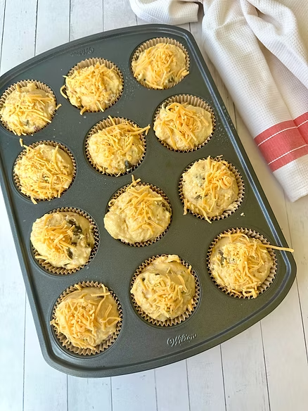 Scoop muffins and fill muffin cup with batter. Garnish if desired with cheese.