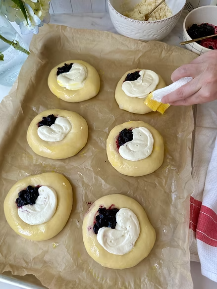 Brush rim with egg wash with a paper towel after filling kolaches and top with crumble
