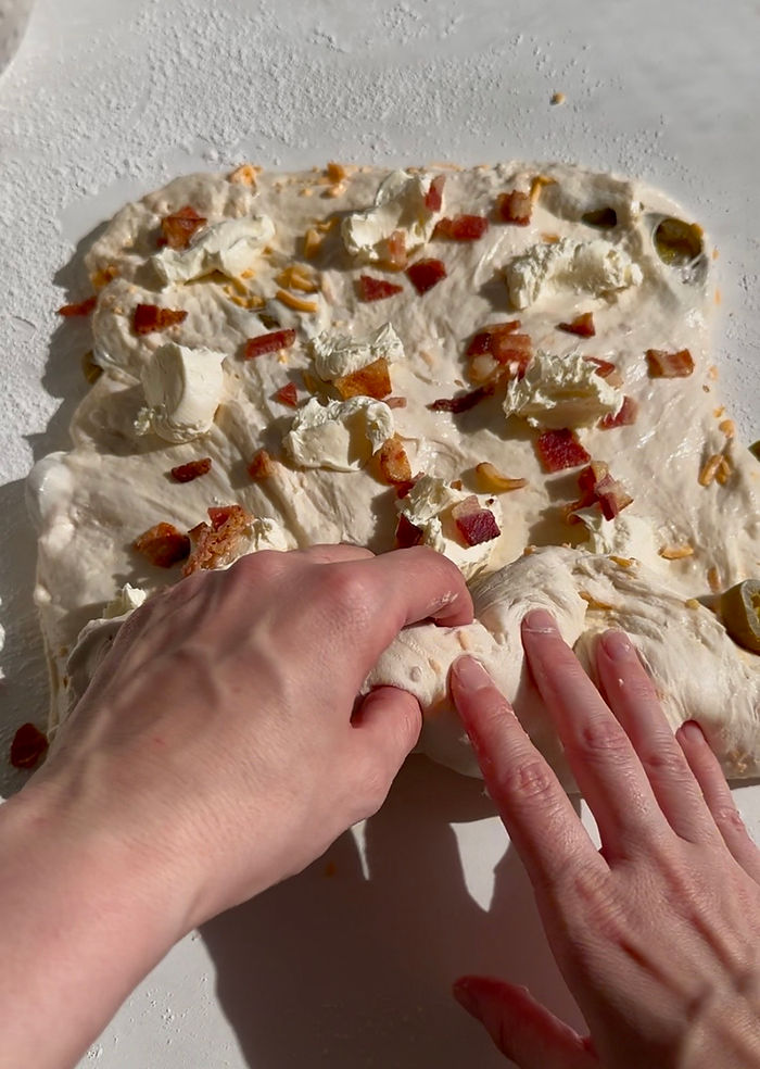 Distribute cream cheese and bacon all over rectangle then roll and shape dough
