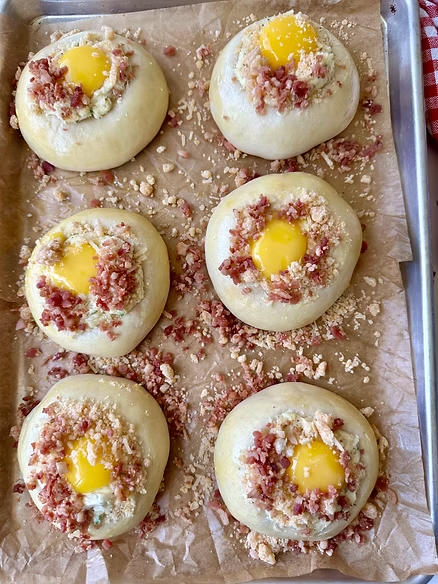 Top kolaches with egg yolk, bacon and crumble then bake again