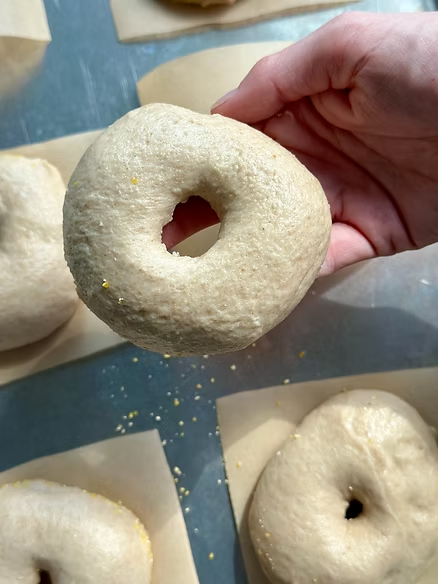 Shape bagels by poking a hole in the center and stretching the dough-transfer to parchment square