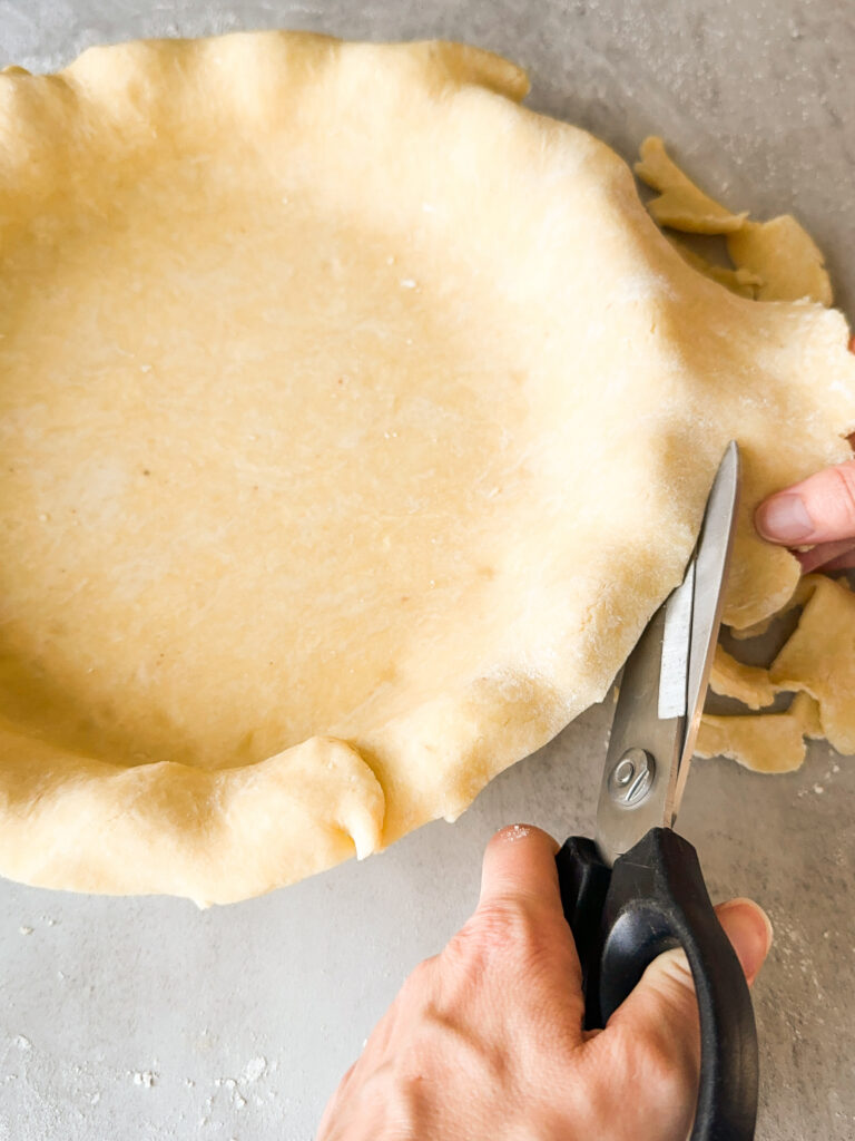 Trim the dough leaving a 1 inch overhang around the pan