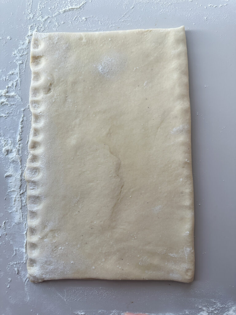 Fold the top half of the rectangle of dough over the half with the cinnamon mixture