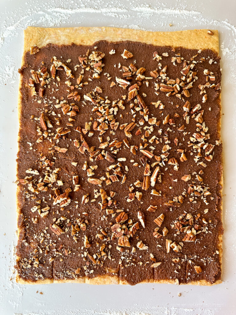 Spread cinnamon filling and pecans over the top of the dough